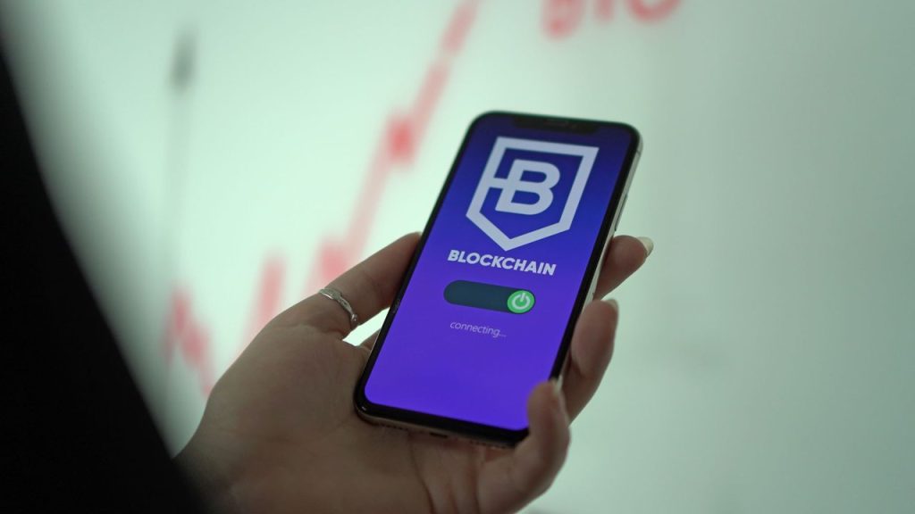 Mão segurando um smartphone com uma carteira digital de criptomoedas exibida na tela.